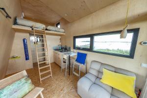 una casetta minuscola con divano e scrivania e cucina di Slapen op de Dijk - Tiny House a Kraggenburg