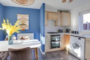 una cocina con paredes azules y una mesa con un jarrón de flores en Cosy 2 bedroom house - With Free Parking and Wifi, en Chelmsford