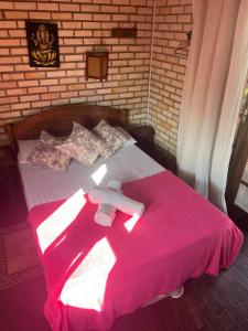 Una cama con una manta rosa encima. en Sol sal cabana p 10, en Imbituba