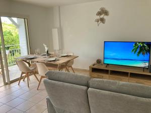uma sala de estar com um sofá e uma televisão em Logement Charme vanillé - Gosier - 2 chambres - Piscine - Wifi - Parking em Le Gosier