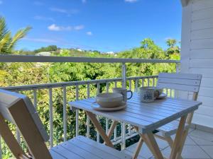 a blue table and chairs on a balcony with a view at Charme Vanillé 2 chambres avec piscine et parking Gosier 5 min plage in Le Gosier