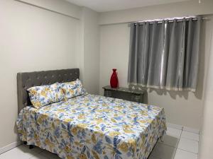 1 dormitorio con 1 cama y un jarrón sobre una mesa en Apartamento em Caruaru a 200m do Pátio do Forró, en Caruaru