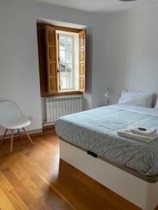 een slaapkamer met een bed met een raam en een stoel bij Apartamento Sarmiento- Casco histórico Mondoñedo in Mondoñedo