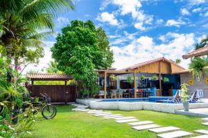 un patio trasero con piscina y una casa en Suite DAVI - Guest House Guaiu en Santa Cruz Cabrália