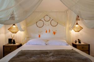 ein Schlafzimmer mit einem weißen Bett und zwei Nachttischen in der Unterkunft Suite DAVI - Guest House Guaiu in Santa Cruz Cabrália