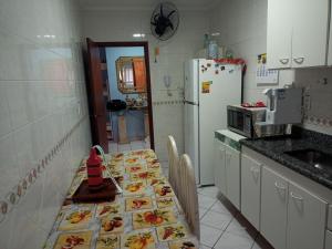 a kitchen with a table and a refrigerator at Apto Pé na Areia Próx Centro Boqueirao PG in Praia Grande +10 photos