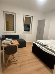 ein Schlafzimmer mit einem Bett und einem Tisch sowie einem Bett und einem Sofa in der Unterkunft Cheema Apartments Frankfurt am Main in Frankfurt am Main