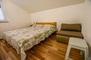 een kleine slaapkamer met een bed en een stoel bij Apartments Ornella in Pašman