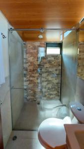 eine Dusche im Bad mit einer Steinmauer in der Unterkunft Cabañas los Sauces in Tota