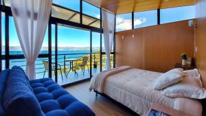 ein Schlafzimmer mit einem Bett und einem Sofa sowie einem Balkon in der Unterkunft Cabañas los Sauces in Tota