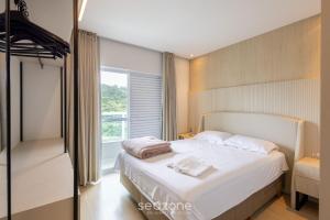a bedroom with a white bed and a window at Apto 2Q moderno prox.da praia STL0702 in Balneário Camboriú