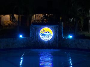 a sign on a wall next to a swimming pool at night at La Rivera Playa Palomino in Palomino +71 photos