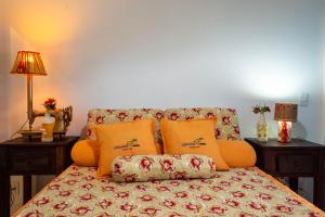 a couch with orange pillows in a living room at Suite LIAM - Guest House Guaiu in Santa Cruz Cabrália