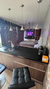 ein Badezimmer mit einem Waschbecken und ein Schlafzimmer mit einem Bett in der Unterkunft Quarto amplo com tv geladeira e fogão in Rio Negro