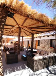 eine Terrasse mit einem großen Strohschirm und Möbeln in der Unterkunft Hostal Katarpe in San Pedro de Atacama