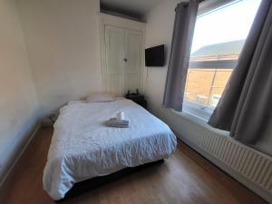 um pequeno quarto com uma cama e uma janela em Handsworth Hostel - Stay Sleep Rest em Birmingham