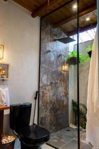 a bathroom with a toilet and a glass shower at Suite NOAH - Guest House Guaiu in Santa Cruz Cabrália