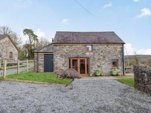 a bird walking in front of a stone house at 2 bed property in Ammanford 87025 in Llandybie