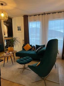 ein Wohnzimmer mit einem grünen Sofa und Stühlen in der Unterkunft Warm apartment + private free park. in Vétraz-Monthoux