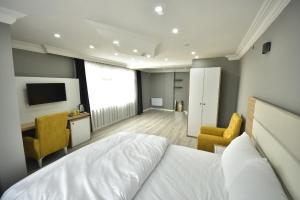 ein Schlafzimmer mit einem Bett, 2 Stühlen und einem TV in der Unterkunft Rio's Hotel AİRPORT in Istanbul