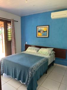 1 dormitorio con 1 cama con pared azul en Sítio Vila das Flores, en Tibau do Sul