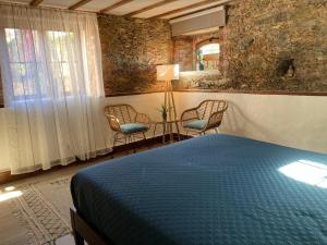 een slaapkamer met een bed, 2 stoelen en een lamp bij A Casa Amarela Guest room in São Martinho da Cortiça