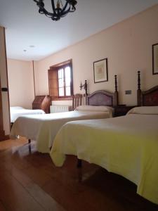 a bedroom with three beds with white blankets on them at El Urogallo in Noceda