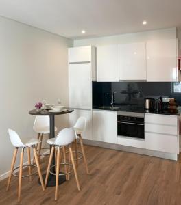 a kitchen with white cabinets and a table and chairs at Vicente´s LOB ( Lobos Ocean Breeze) in Câmara de Lobos
