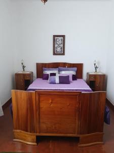 a bedroom with a wooden bed with purple sheets at Casa da Atalaia in Angra do Heroísmo