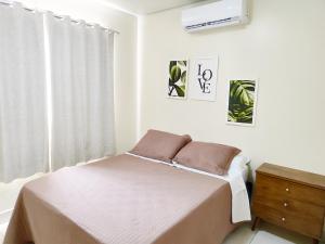 a white bedroom with a bed and a window at Condomínio Capim Santo in Goiânia