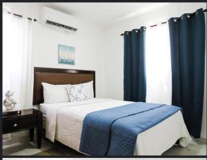 een slaapkamer met een groot bed en blauwe gordijnen bij Beautiful condo in La Romana near Caleta beach in La Romana