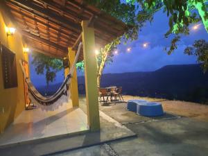 a house with a hammock on a patio at night at Chalé na Serra in Mulungu