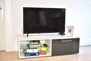 a flat screen tv sitting on top of a entertainment center at Lux 2-Bed Apt Central Location Balcony & Parking in Reading