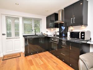 a kitchen with black cabinets and a microwave at 1 Bed in Charlestown 53680 in Luxulyan