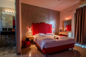 une chambre avec un grand lit avec une tête de lit rouge dans l'établissement Irinis Garden, à Parga 63 autres photos