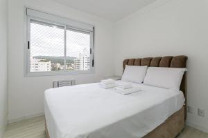 a large white bed in a white room with a window at WI-FI 600mb | 500m da UFSC #TRINA02 in Florianópolis