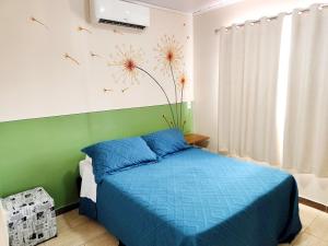 a bedroom with a blue bed and a green wall at Condomínio Capim Santo in Goiânia