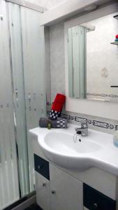 ein Badezimmer mit einem weißen Waschbecken und einem Spiegel in der Unterkunft Ferienwohnung mit Dachterrasse, mehreren Pools, Garten und viel Ruhe in Poris de Abona