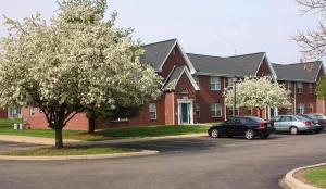 a red brick house with cars parked in a parking lot at 2 bedroom apartment RivianISU in Bloomington