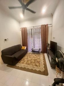 a living room with a couch and a tv at Homestay Seri Aman Pasir Puteh 