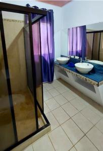 zwei Waschbecken im Badezimmer mit lila Vorhängen in der Unterkunft Il Padrino Corcovado Apartament in Puerto Jiménez