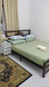 a bedroom with a bed with a green bedspread and a rug at Homestay Seri Aman Pasir Puteh 