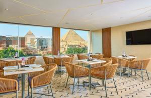 a restaurant with tables and chairs and a view of the pyramids at Cleopatra Tower Pyramids View in Cairo