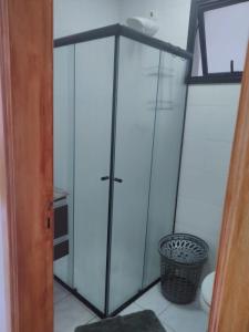 une armoire en verre dans une pièce avec une poubelle dans l'établissement Apto Aconchegante, à Praia Grande