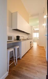 MILAN design Loft-Hosted by Sweetstay في ميلانو: مطبخ بدولاب بيضاء وأرضية خشبية