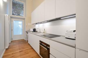 MILAN design Loft-Hosted by Sweetstay في ميلانو: مطبخ مع دواليب بيضاء ومغسلة