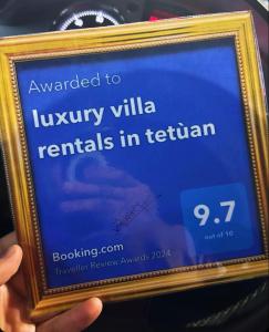 una persona che tiene un cartello con la scritta che legge il premio per gli affitti di ville di lusso in t di luxury villa rentals in tetùan a Tétouan