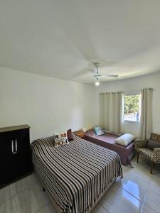 um quarto com uma cama, um sofá e uma janela em Bertioga Praia do SESC - Apartamento de 2 quartos em Bertioga