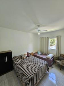 a bedroom with a bed and a couch and a window at Bertioga Praia do SESC - Apartamento de 2 quartos in Bertioga