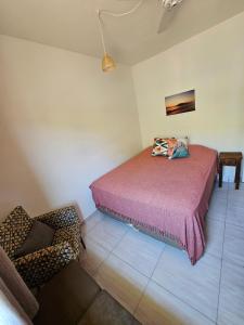 um quarto com uma cama e uma cadeira em Bertioga Praia do SESC - Apartamento de 2 quartos em Bertioga